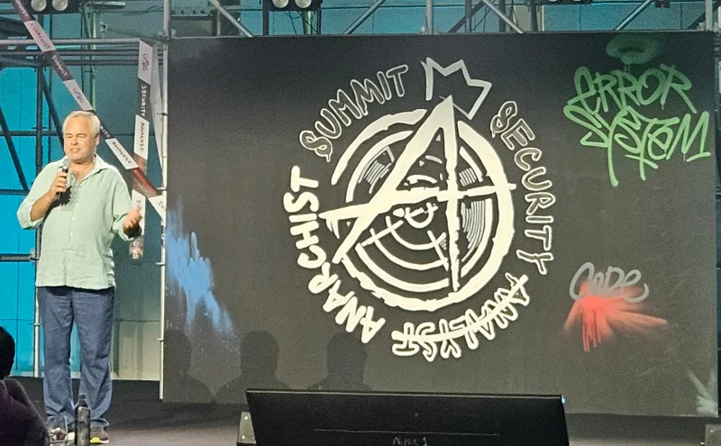 Eugene Kaspersky berbicara di panggung Security Analyst Summit 2026 dengan logo bertema anarki